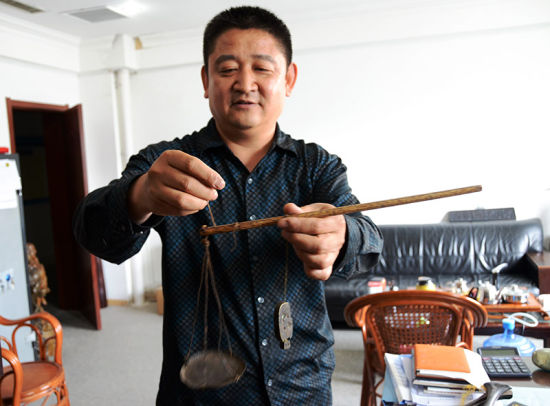 秤砣收藏家张奎生正在展示罕见的子母秤