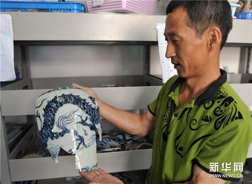 考古工作人员展示的落马桥窑遗址出土元青花瓷器残片上有明显的锐物击打痕