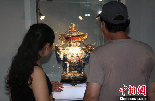 观众在欣赏张同禄为献礼祖国60华诞而创作的景泰蓝作品《扭转乾坤）