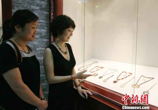 来自重庆的珠玉收藏鉴定家洪艺宁（右）向参观者介绍“蜻蜓眼”。　邓霞　摄