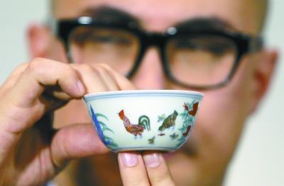   4月8日，苏富比亚洲区副主席仇国仕在拍卖结束后向记者展示成交价高达2.8124亿港币的明成化斗彩鸡缸杯。新华社发