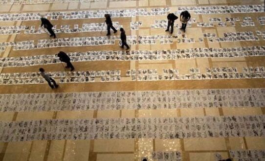        阅卷现场，一幅幅考试画卷铺满了大厅，评委老师手拿长棍在画面上指指点点，认真判卷。