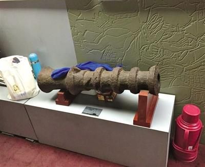 古代钱币展览馆，一古炮旁放着水壶等物品，还有一块抹布搭在铁炮上。