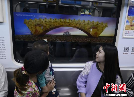   在长沙地铁内，市民欣赏湘籍艺术家舒勇创作的作品《丝路金桥》。　