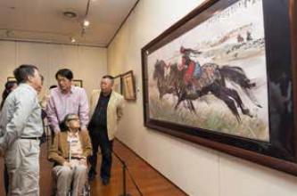第一届黄胄艺术收藏大展展览现场，黄胄夫人郑文慧女士观看《草原逐戏图》。 