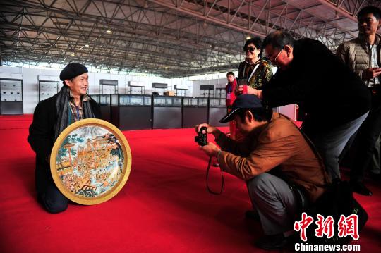  图为藏友王声伟向收藏爱好者展示“描金洋彩水浒英雄图撇口折沿大盘”。　刘冉阳　摄