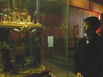   王津凝望自己参与修复的铜镀金雄鸡动物座楼阁式钟。曾洁摄