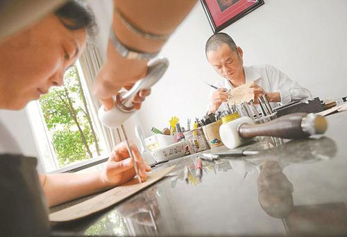 　　张伟(右)将皮雕技术创新融入年画创作中，让绵竹年画动感十足。