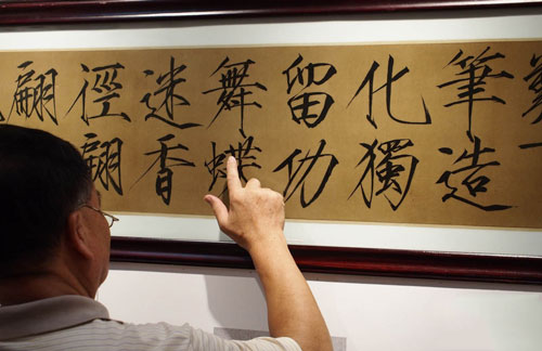 一位书法爱好者在墨宝瓷板上揣摩笔意