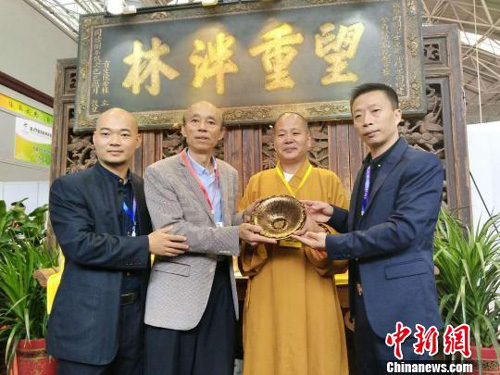 由中国高级工艺美术师，非物质文化遗产建盏技艺传承人黄美金（左二）创作的金油滴撇口盏，被来自福建福清的著名慈善家陈先生和万福禅寺方丈悲升大师（右二）以299万元购得。　李加林　摄　