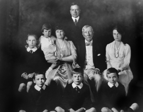 （图：洛克菲勒家族在1920年的家族画像，其中站立者为小洛克菲勒，第二排左二被抱着的孩童是大卫·洛克菲勒)）