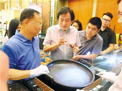 西泠印社拍卖有限公司总经理陆镜清（左二）向观众讲解兮甲盘的来历。 深圳商报记者 胡云涌 摄