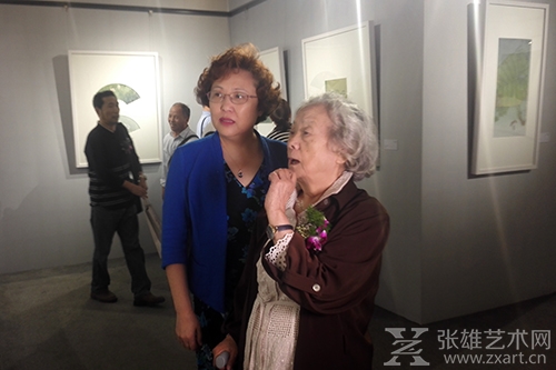  中国美术家协会中国重彩研究会会长、中央美术学院教授蒋采苹女士正在认真观赏画作