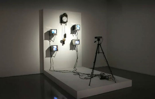  白南准，《法式钟表电视》，1993，法式挂钟、9英寸真力时显示器、索尼CCD彩色摄像机、射频放大器、线缆及调制器、相机三脚架、变压器、BNC/RCA视频电缆，尺寸可变.